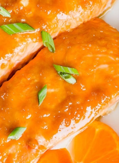 Horizontal image of orange ginger baked salmon filets next to a bowl of white rice.