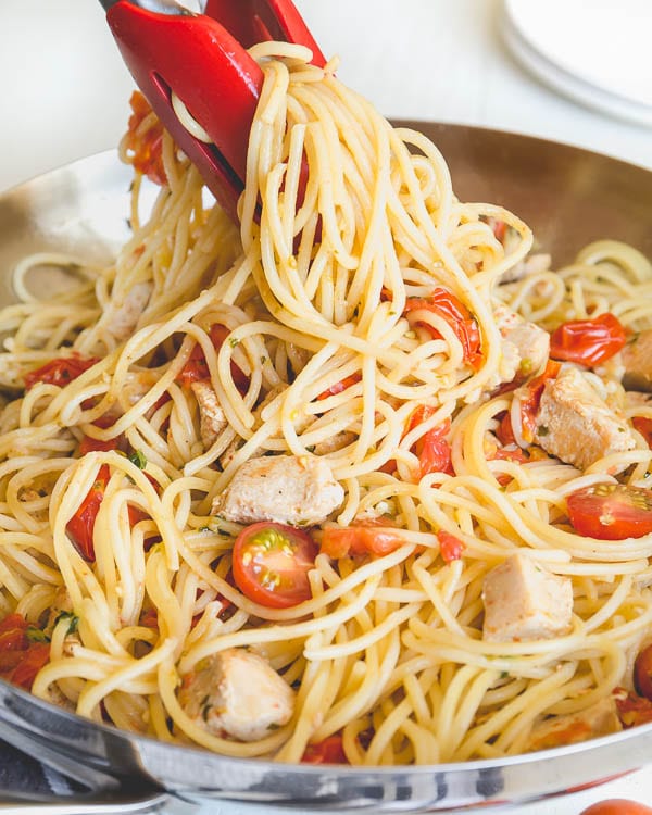 Chicken and cherry tomato pasta in a stainless steel skillet.