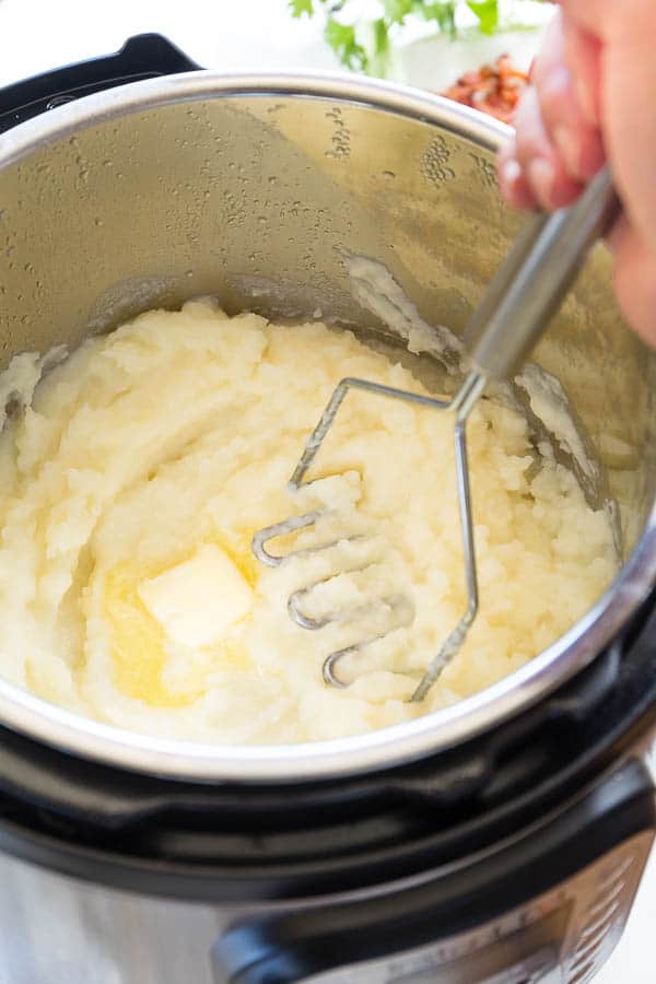 Instant Pot mashed potatoes being mashed with butter. 