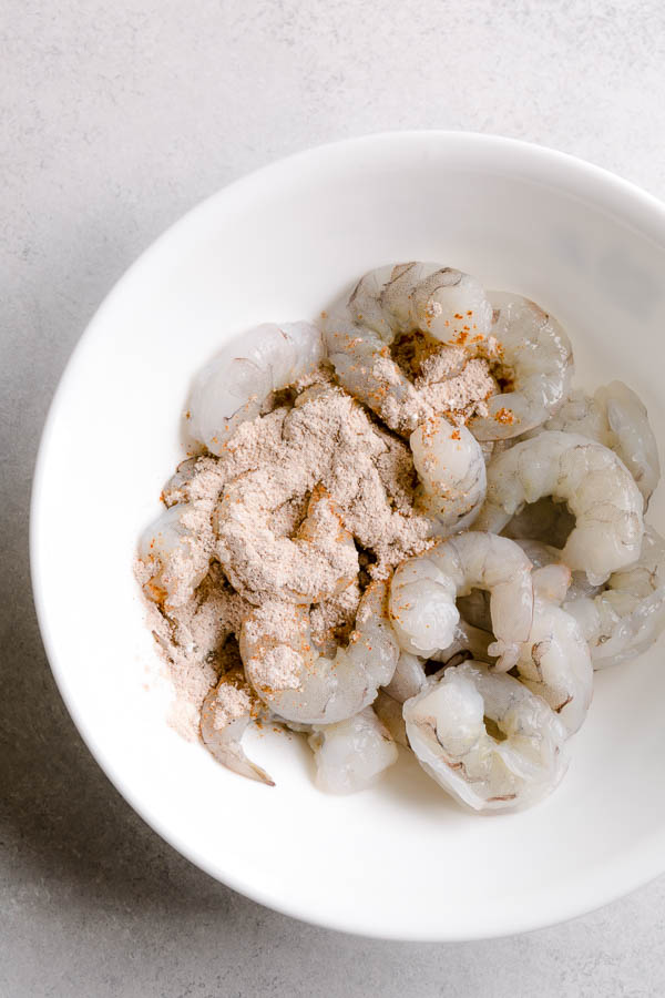 A bowl of raw shrimp with cornstarch mixture on top. 