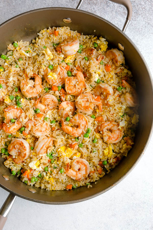 A skillet of shrimp fried rice with vegetables and eggs. 