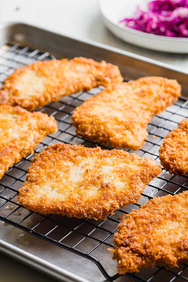 Breaded pork cutlets on a wire rack. 