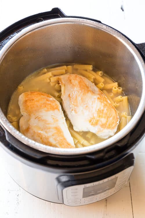 Layer the pasta, chicken stock and chicken breasts in your Instant Pot for this creamy dreamy Instant Pot chicken alfredo pasta in less than 30 minutes, half of which is inactive time!!! Effortlessly easy, kid-approved comfort food! #instantpotrecipe #weeknightrecipe #busycooks #easydinner #instantpotpasta