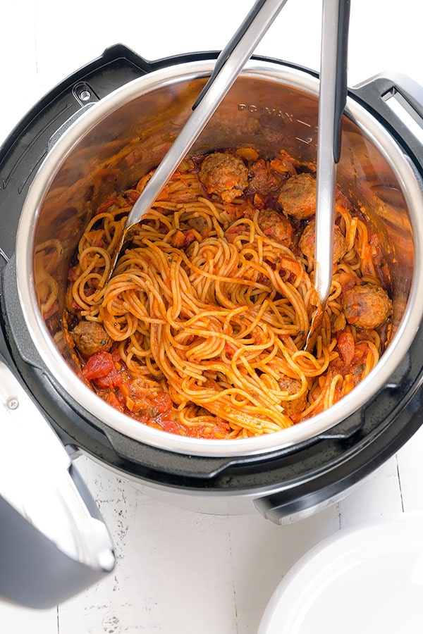 Spaghetti and meatballs in an Instant Pot with tongs sticking out. 