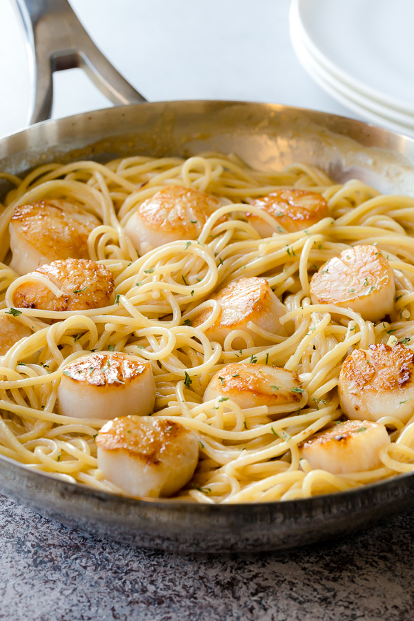A skillet of scallop pasta with white wine sauce. 