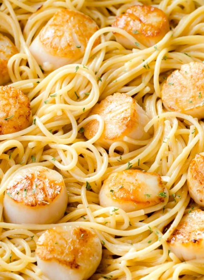 Scallop pasta with white wine sauce in a skillet.