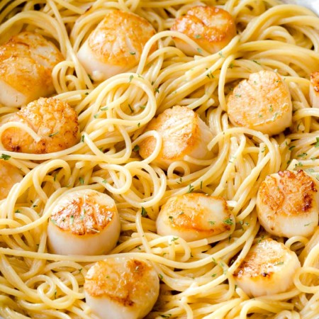 Scallop pasta with white wine sauce in a skillet.
