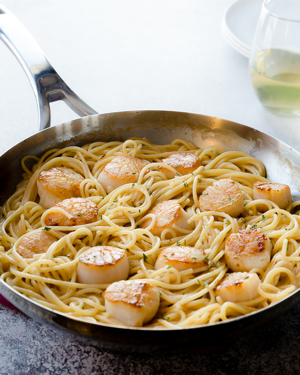 A skillet of scallops pasta with white wine sauce. 