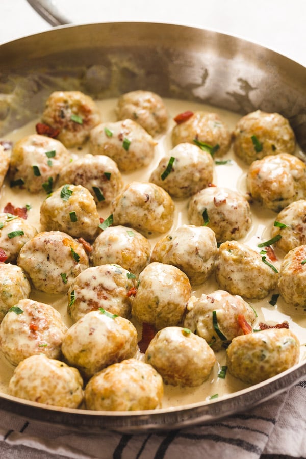 A skillet full of bacon chicken meatballs in bacon cream sauce. 