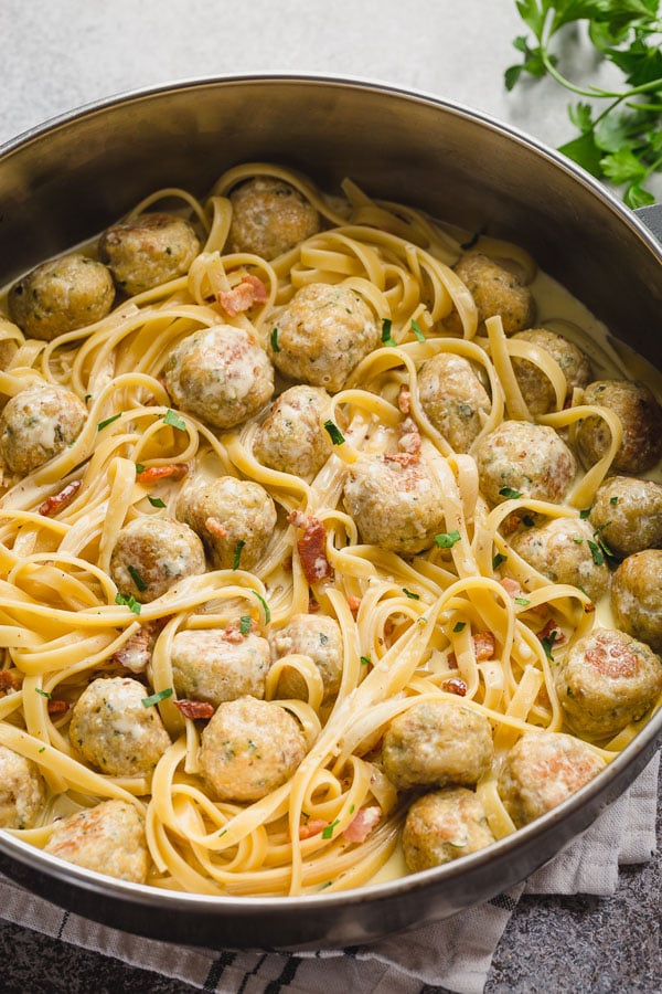 A skillet full of bacon chicken meatballs with pasta. 