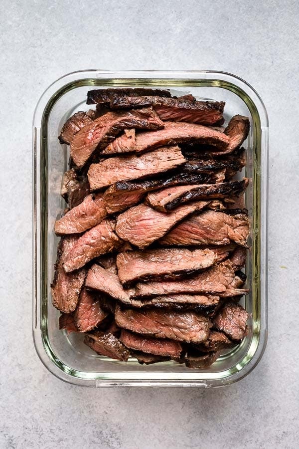 Leftover steak is cut into thin strips in a glass dish.