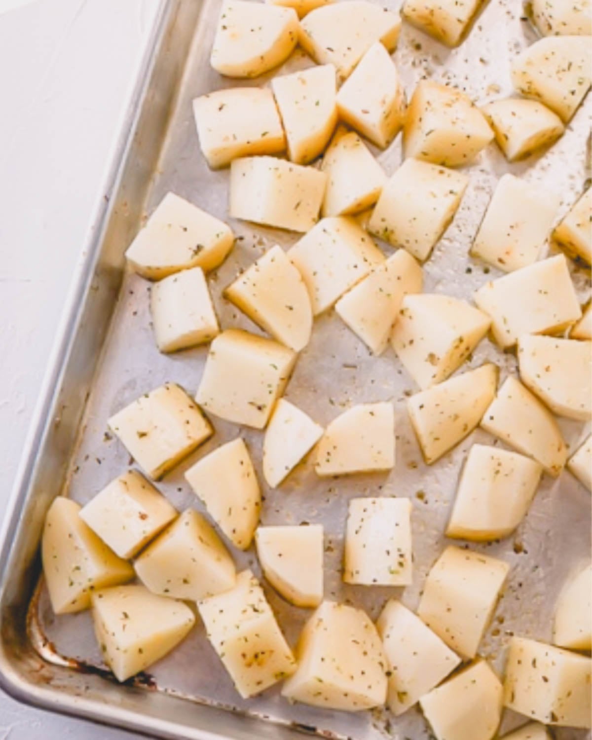 Cut up potatoes seasoned and laid in a single layer on a baking sheet.