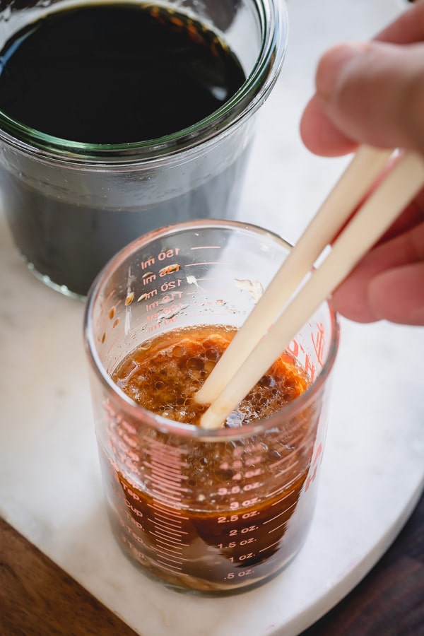 Mixing stir fry sauce in a measuring cup with chopsticks.