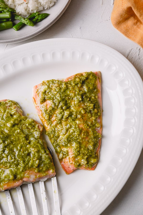 Two pieces of pesto salmon on a plate. 