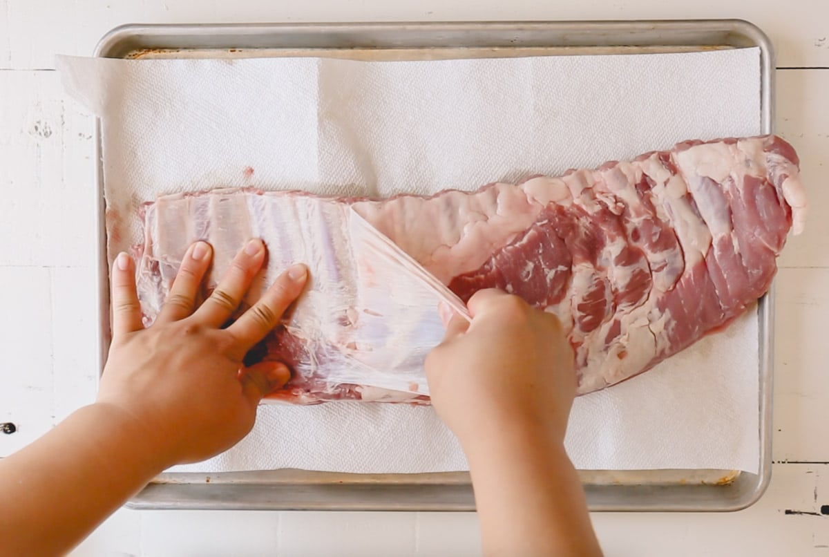 A hand pulling the membrane from the back of ribs.