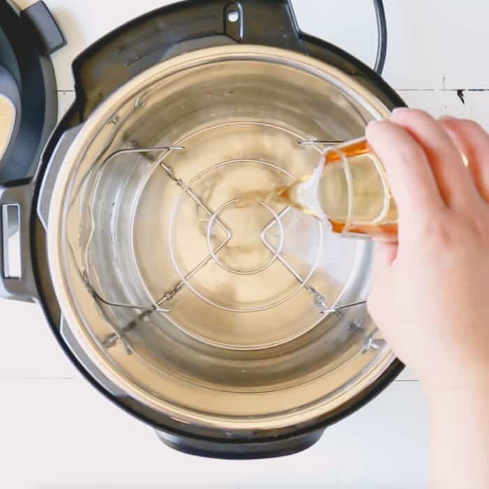 Adding apple cider vinegar into the Instant Pot.