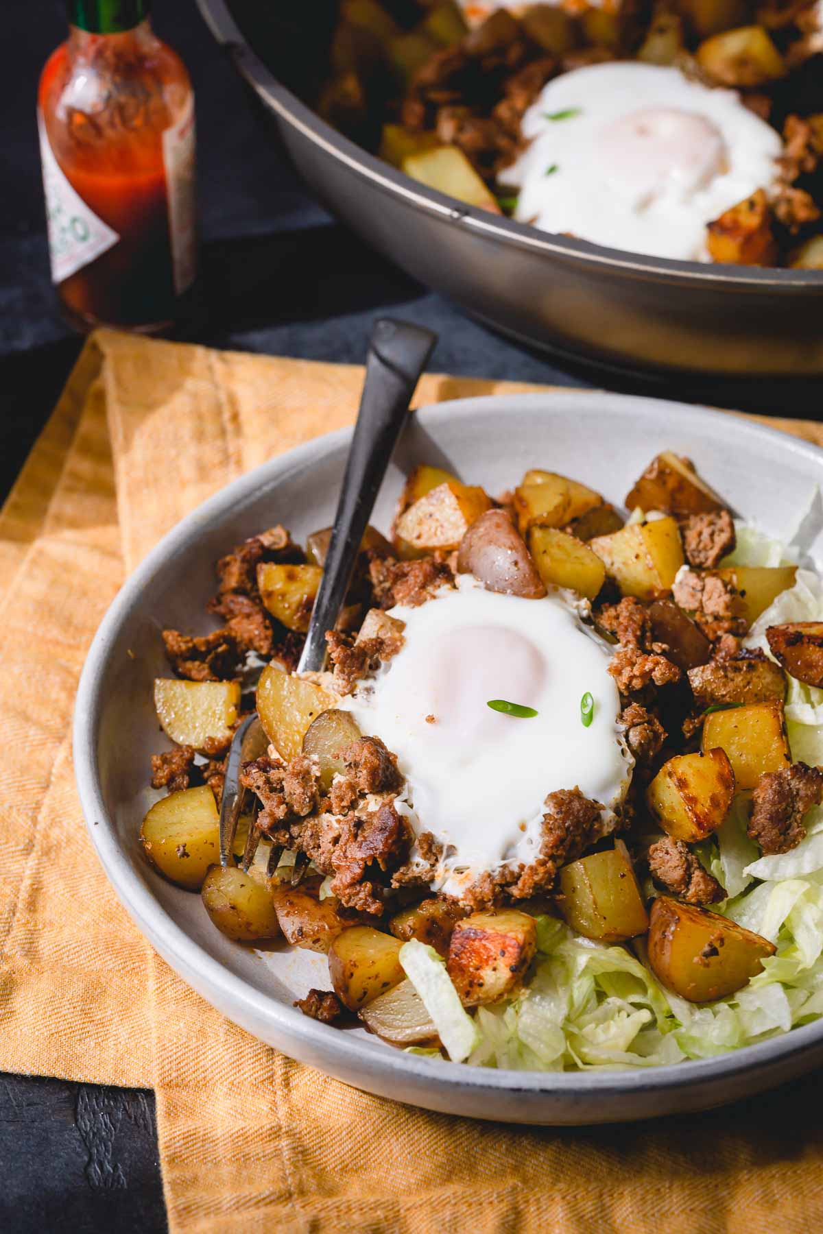 Ground beef potato hash with an egg in a grey bowl. 