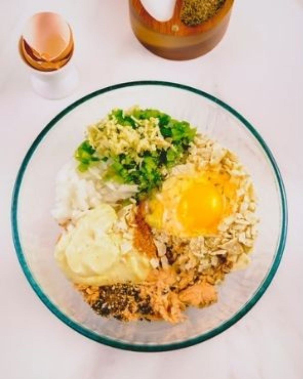 All the ingredients for salmon patties dumped in a glass bowl.