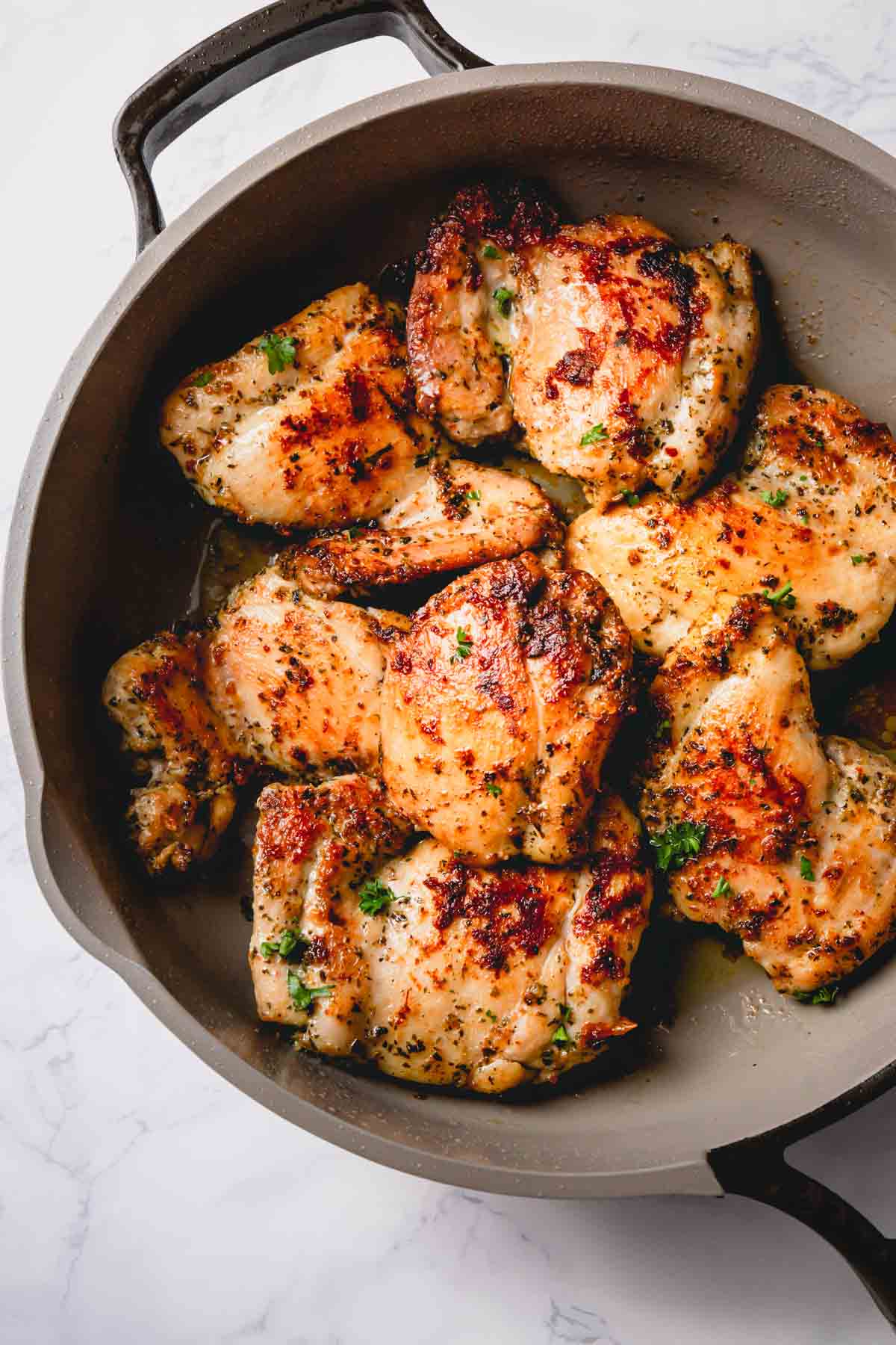 Pan seared skinless chicken thighs in a skillet.