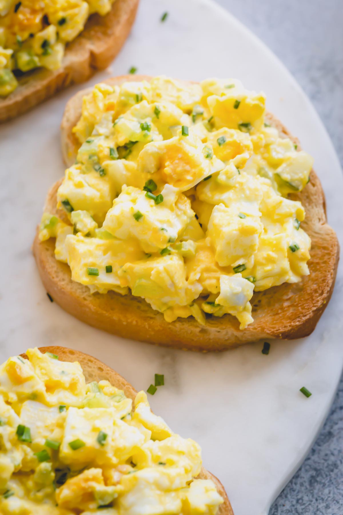 Egg salad on a toast and garnished with chopped chives.