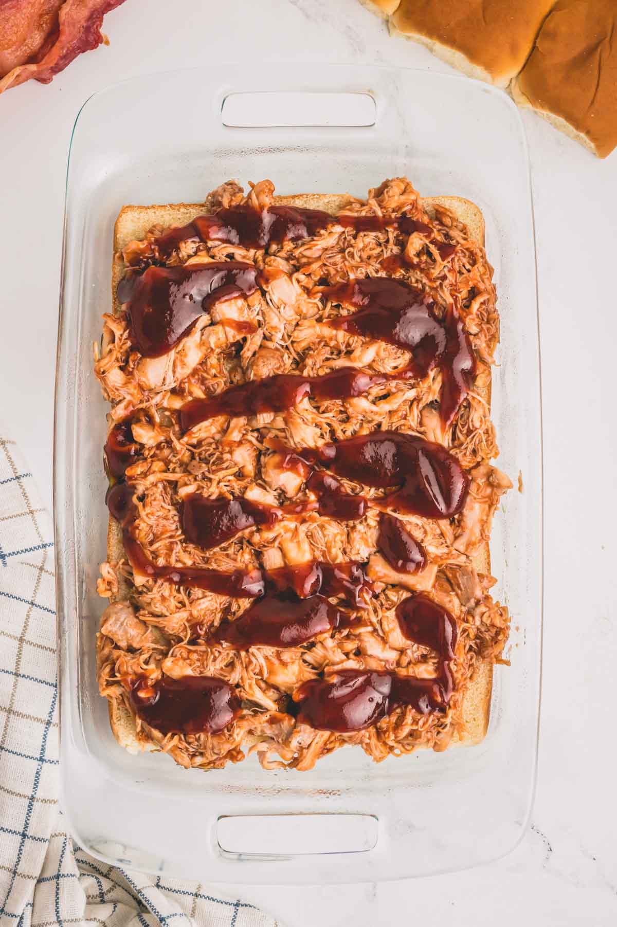 Slider rolls topped with bbq chicken and more bbq sauce on top.