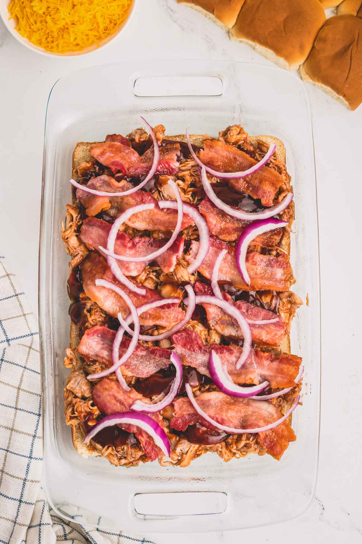 Cooked bacon strips and red onion slices over a bbq chicken mixture.