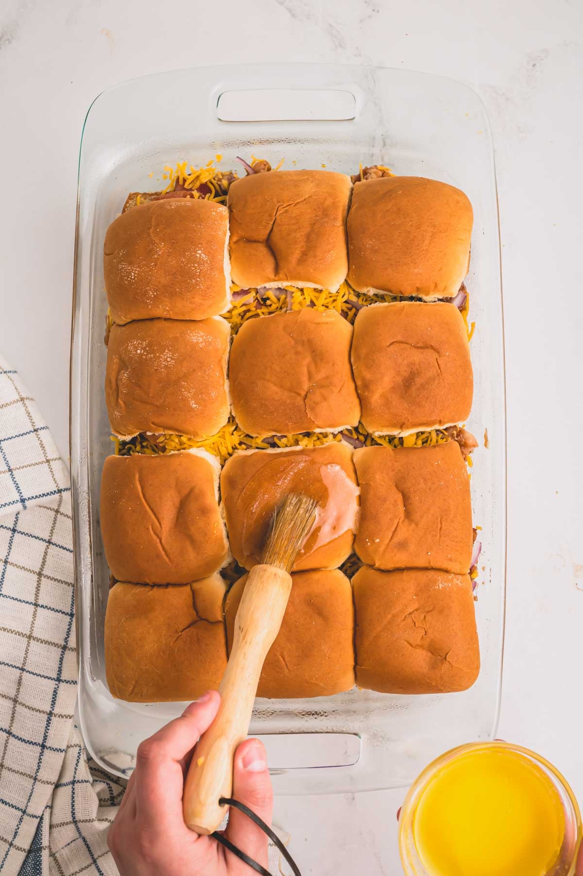 Top slider rolls are placed over bbq chicken mixture and brushing on melted butter over the rolls.