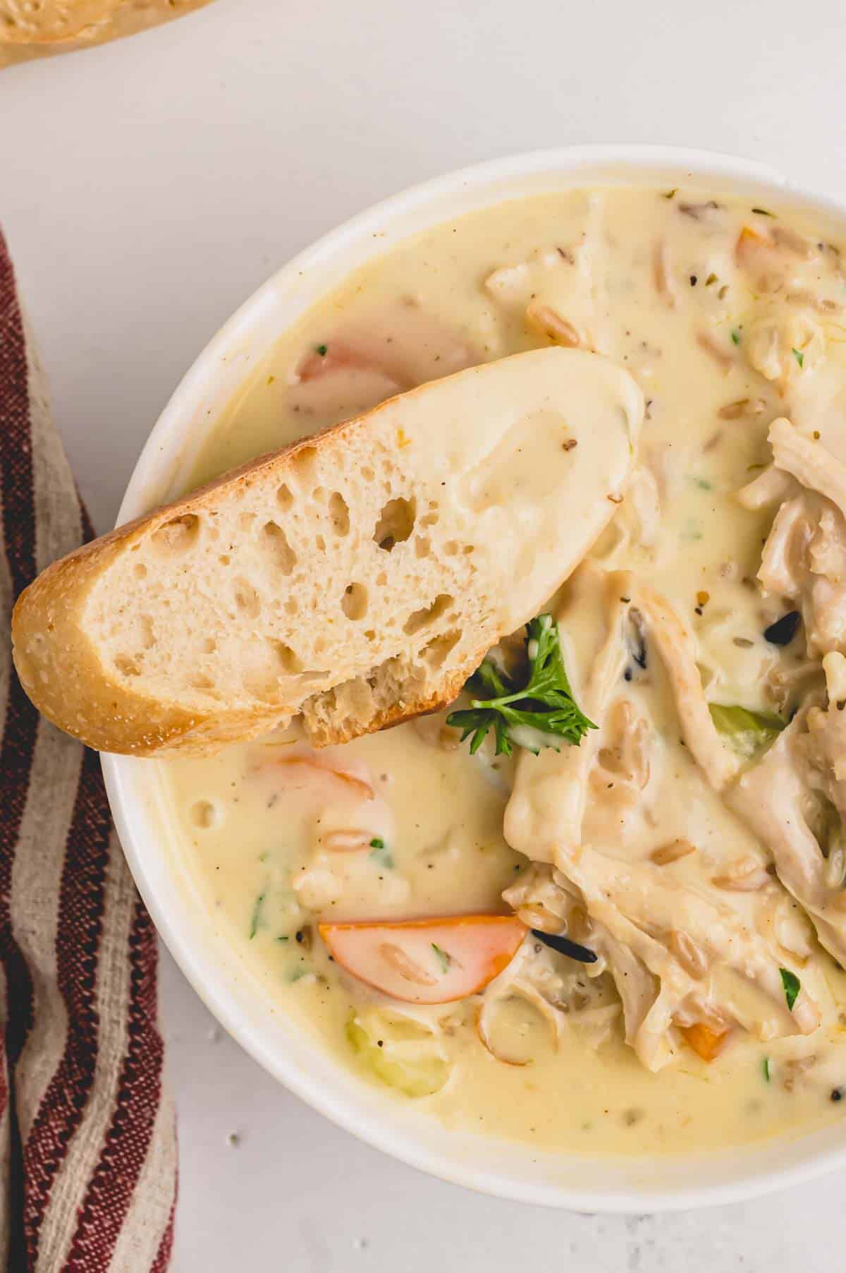 Creamy leftover turkey soup in a bowl with a slice of bread.