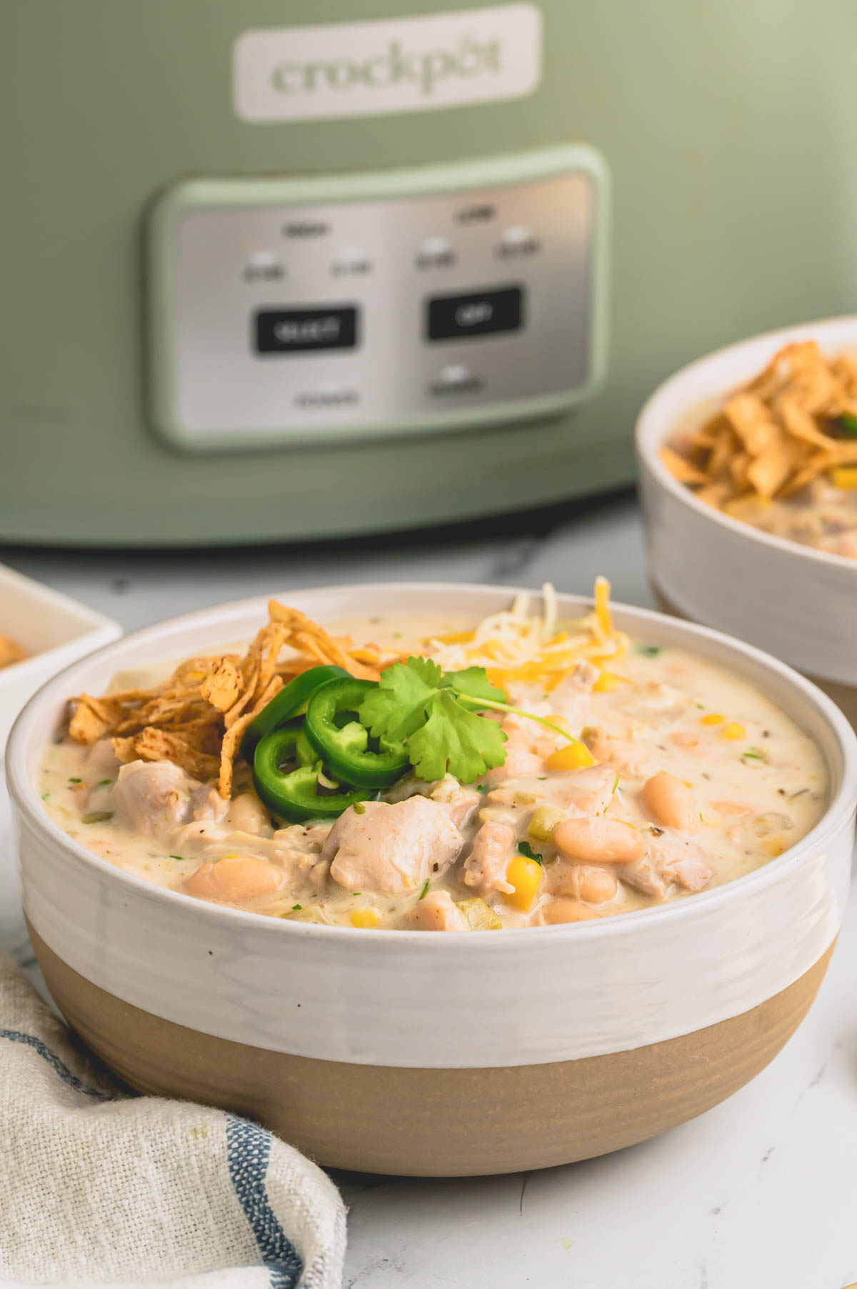 a bowl of white chicken chili with jalapenos on top.
