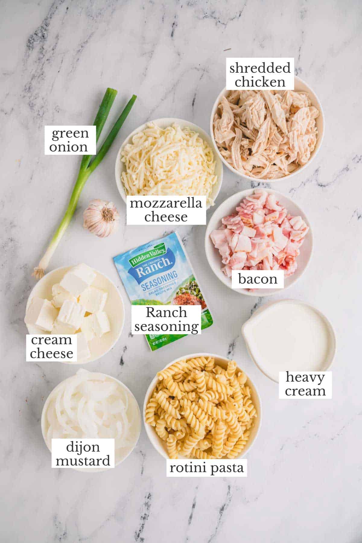Ingredients to make chicken bacon ranch casserole with shredded chicken and rotini pasta.