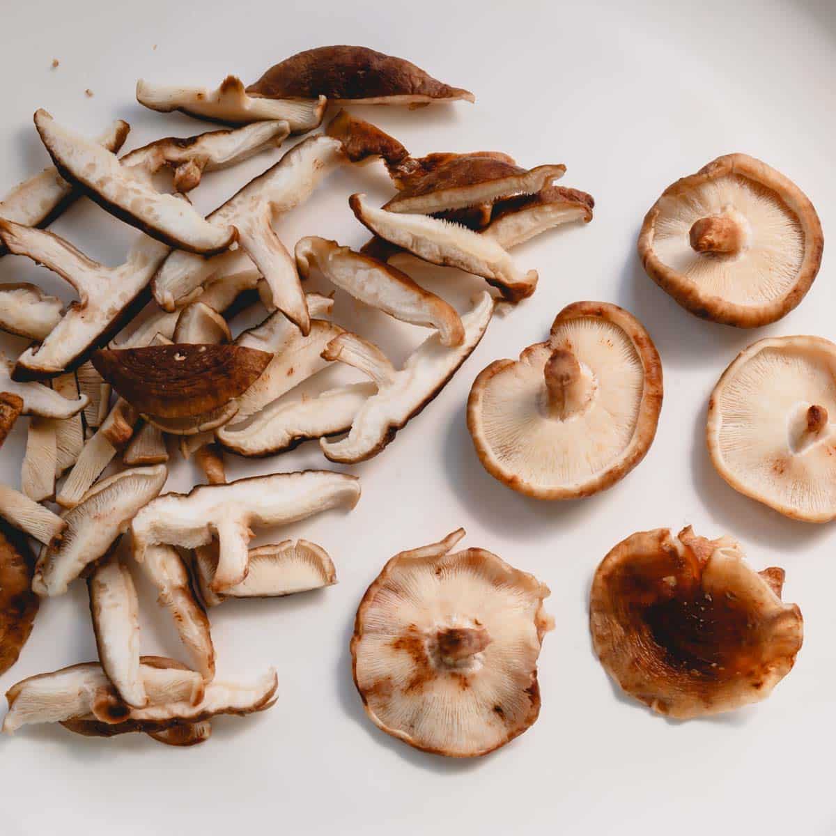 Shiitake mushrooms and white mushrooms on a cutting board.