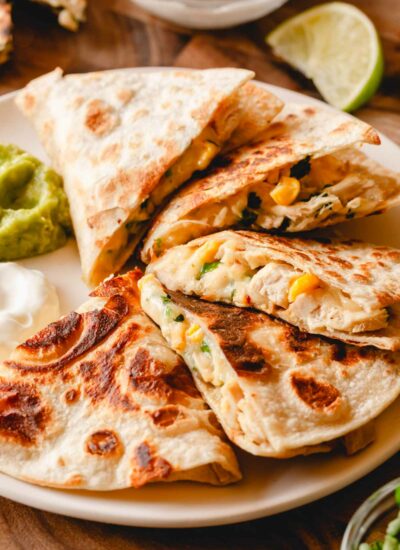 An easy chicken quesadilla on a plate with guacamole and sour cream.