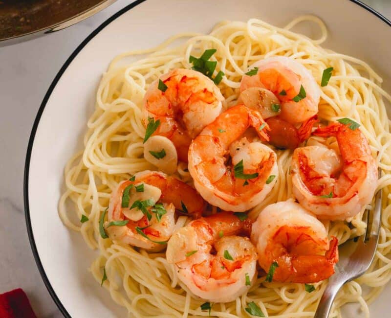 A plate of garlic butter shrimp pasta with a fork.