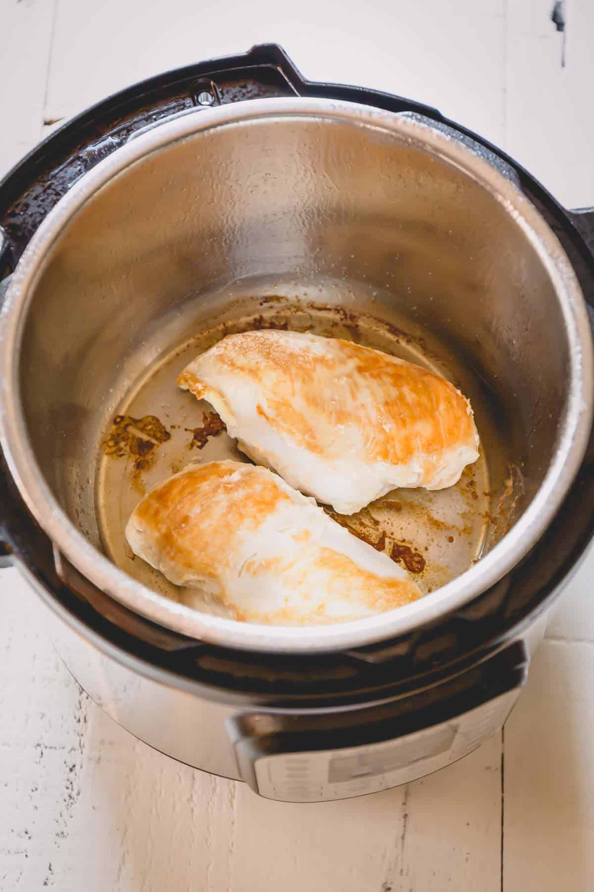 Two cooked chicken breasts in an Instant Pot.