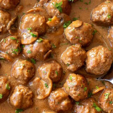 Meatballs and gravy with mushrooms topped with fresh herbs.
