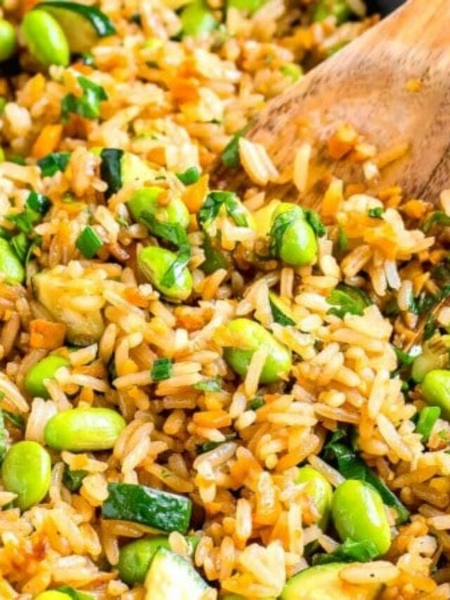 Close up image of sweet potato fried rice being stirred with a wooden spoon.