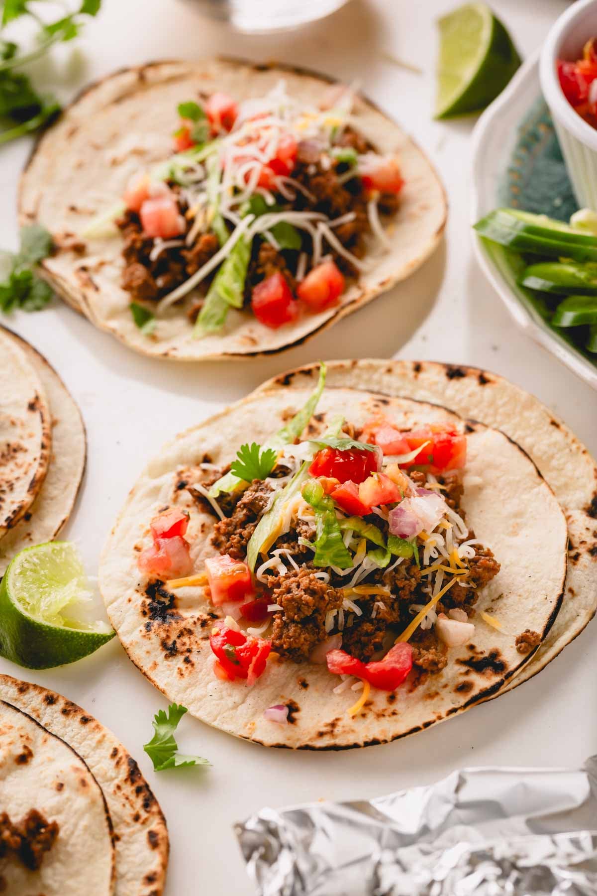 Tortilla shells topped with taco meat, pico, cheese, lettuce, and cilantro.