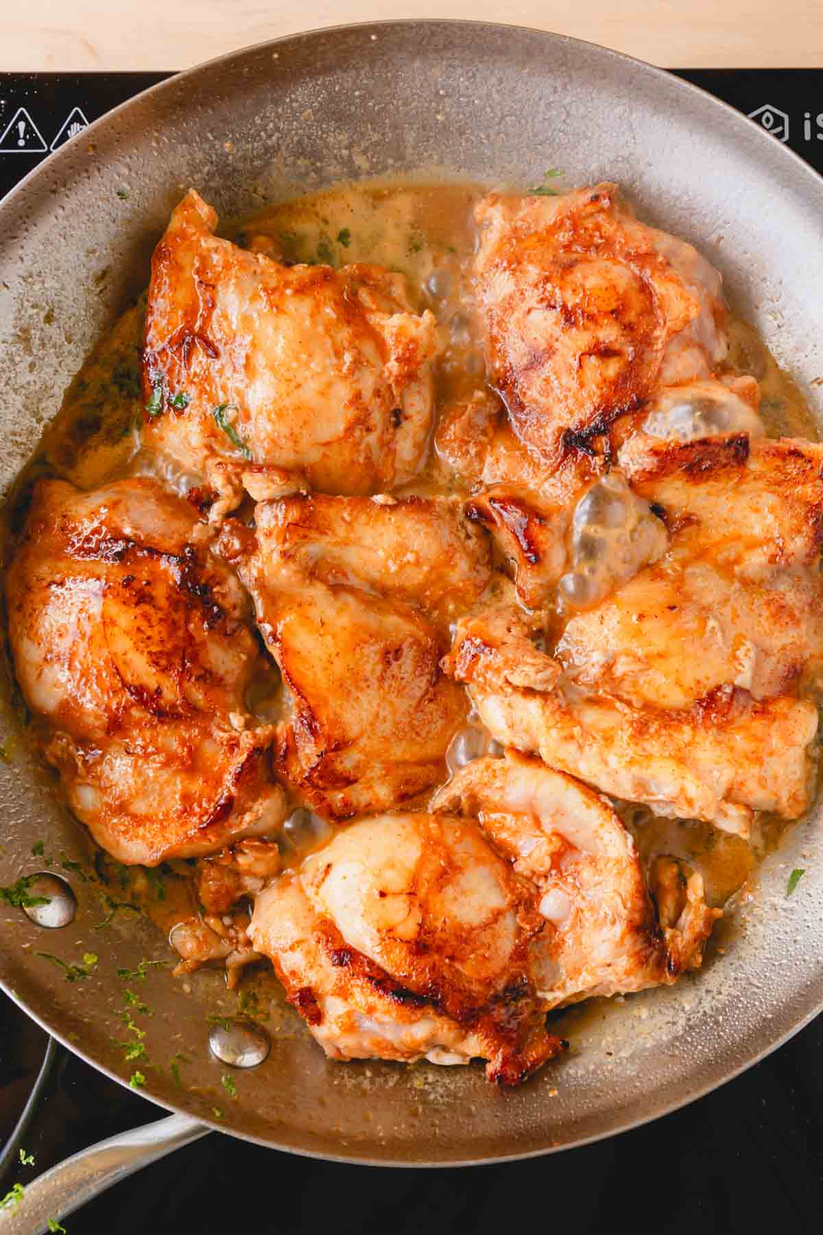Chicken thighs are in a skillet.