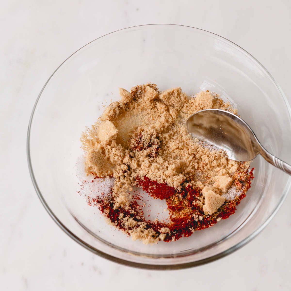 Brown sugar, cumin, smoked paprika, and salt in a small bowl with a spoon.