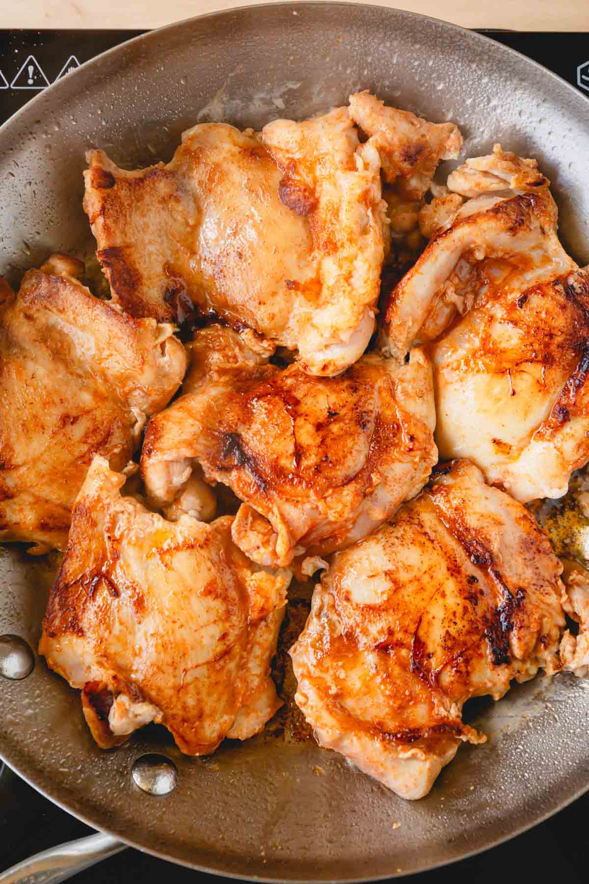 Chicken thighs are in a skillet.