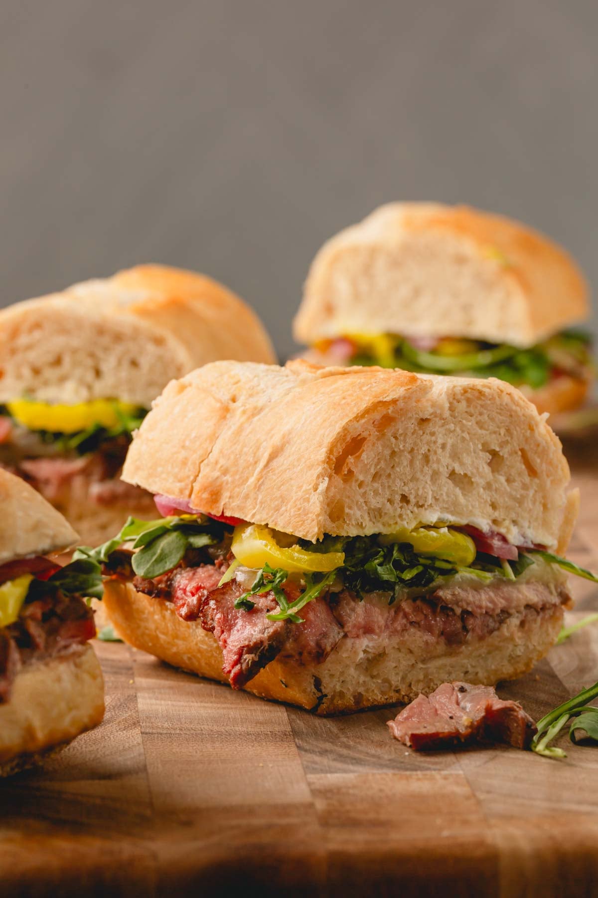 Ribeye steak sandwiches on a wooden cutting board.