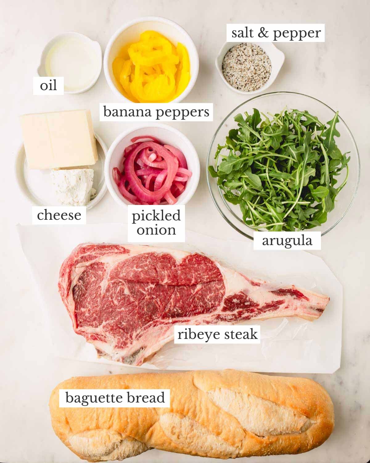 Ingredients to make a ribeye steak sandwich with baguette bread.