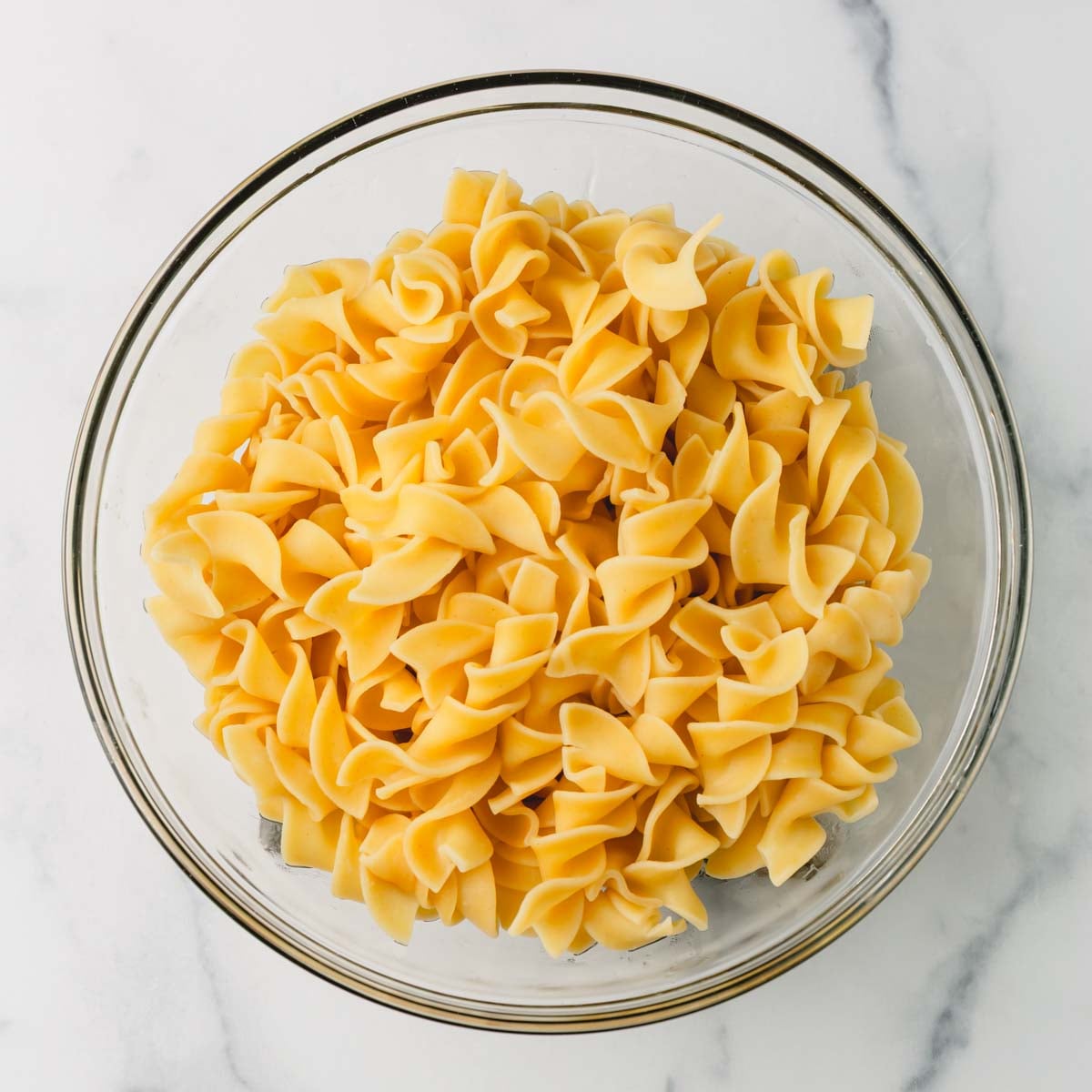 Cooked egg noodles in a glass bowl.