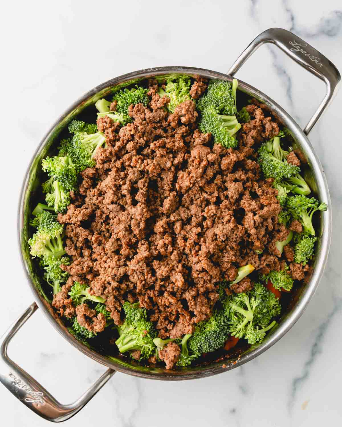 Ground beef and broccoli are added to the large skillet.