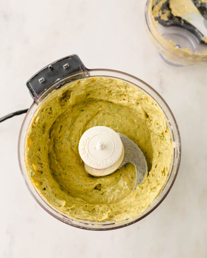 Avocado crema ingredients are blended until smooth and creamy in a food processor.