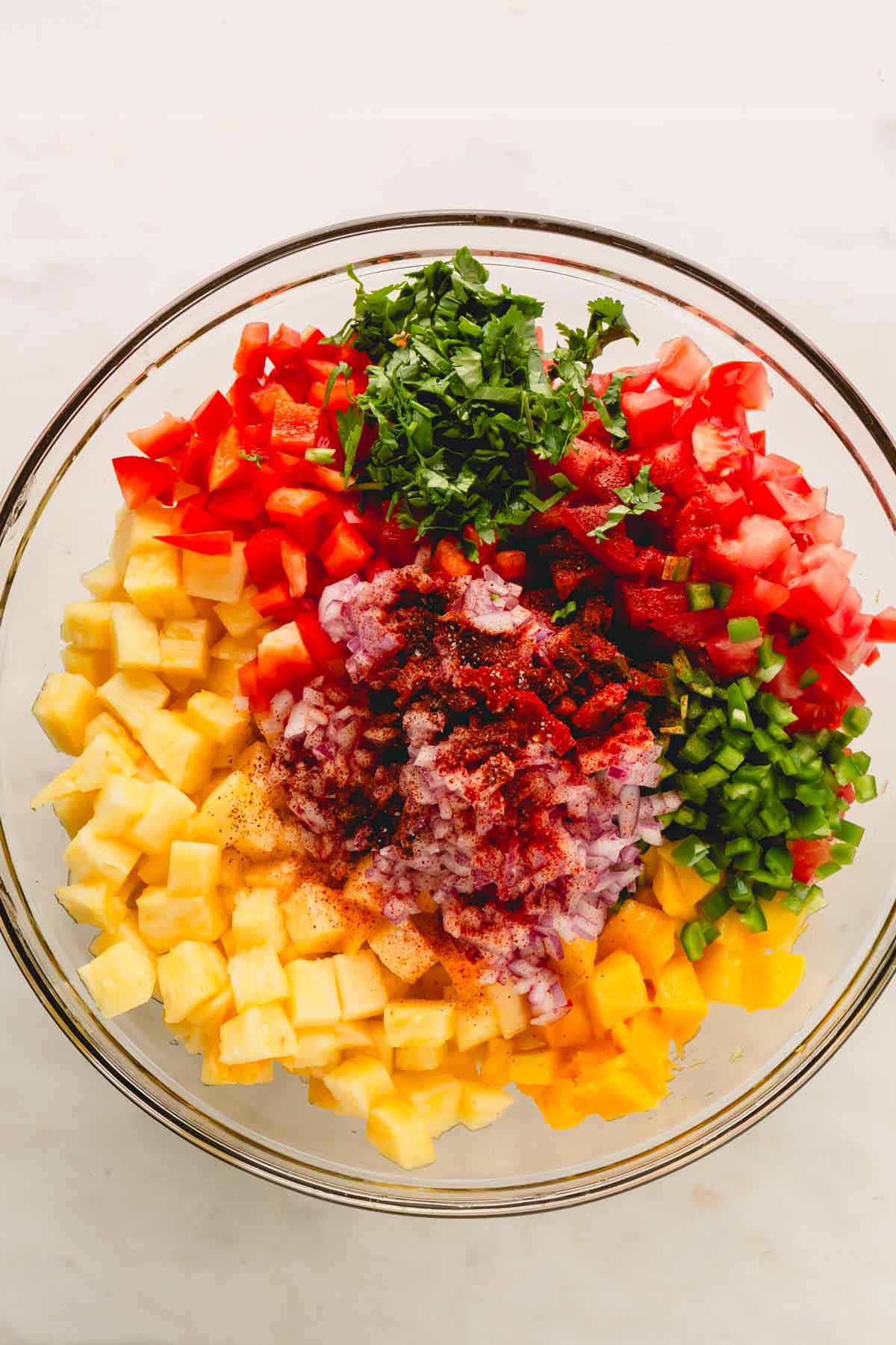 Ingredients for pineapple mango salsa in piles in a bowl.