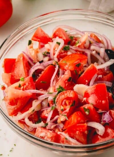 Tomato onion salad in a glass bowl.