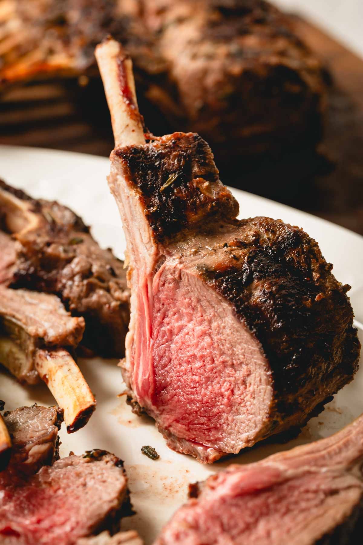 A grill lamb chop is standing up on a plate.