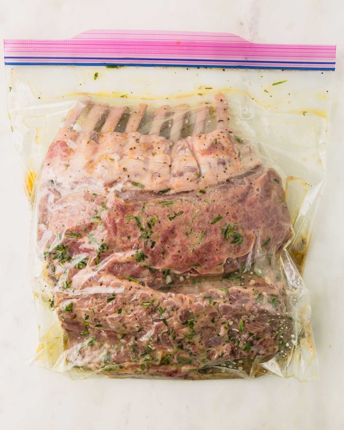 Racks of lamb are in a marinade in a zip top bag.