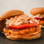 Spicy chicken burgers on a black surface.